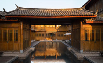 Swimming pool at Amandayan, China, framed by traditional architecture at dusk.
