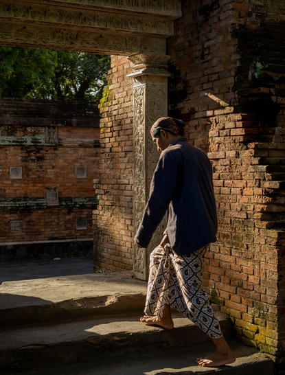 Guest walking through a stone archway at Amanjiwo, Yogyakarta.