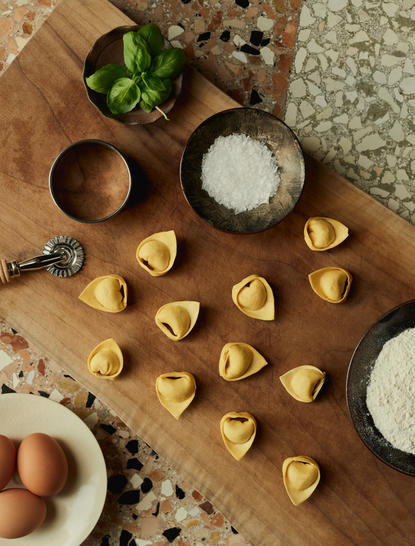 Freshly made pasta shapes arranged on a wooden board at Aman Venice, with bowls of flour and ingredients nearby.