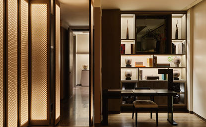 Corner Suite con zona living in legno scuro presso Aman New York hotel.