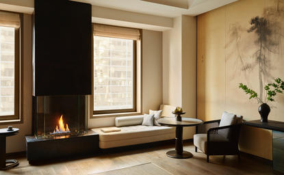 安缦纽约酒店第五大道初级套房，壁炉旁配有坐卧区和大窗户。