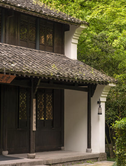 法云安缦度假村的传统中式建筑入口，深色木门配白色墙面，周围绿植繁茂。