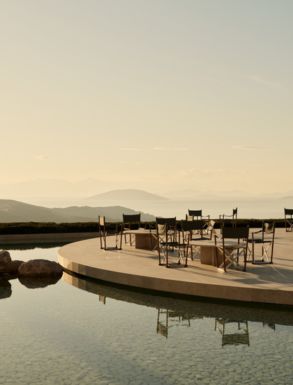 Exterior bar at Amanzoe resort overlooking still waters at dusk, Greece.