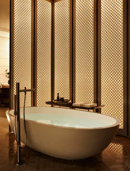Salle de bain de la Grand Suite à Aman New York, avec baignoire autoportante et panneau en bois.