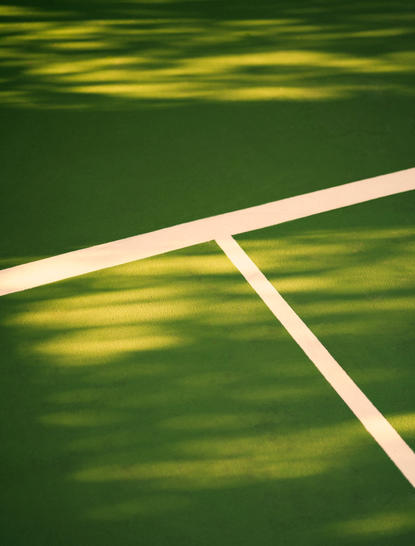 Amandari 리조트의 테니스 코트 세부 사항, 흰색 라인과 초록색 코트 표면.