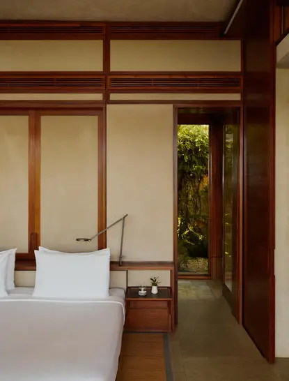 Principal bedroom at Amanera with wooden beams, paper screens and view through to garden.