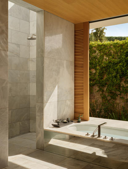 Villa bathroom with walk-in shower, soaking tub and view of olive groves at Amanzoe resort.