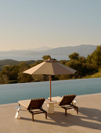 Villa terrace with two lounge chairs and umbrella overlooking the Aegean Sea at Amanzoe resort.