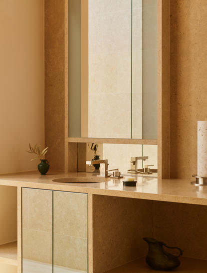 Bathroom vanity at Amanzoe with warm timber cabinetry and tall mirror, minimal styling visible.