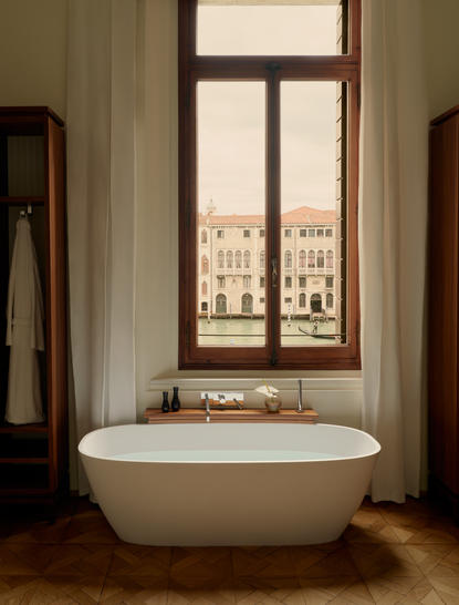 アマン ヴェニスのバスルーム。グランドカナル運河を見下ろす窓の前に置かれた白い浴槽。