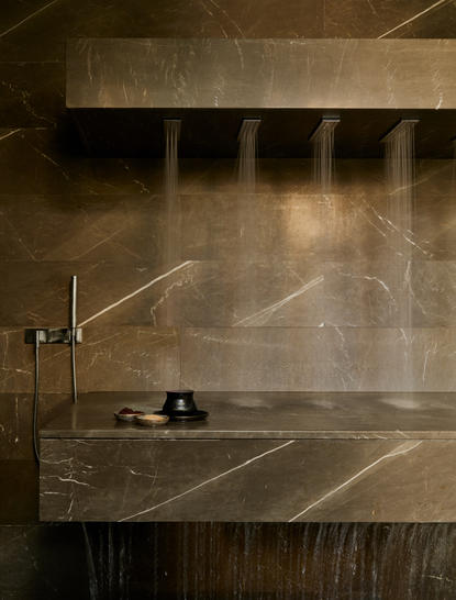 Detalhes do spa banya no Aman New York, com parede de mármore e vapor.