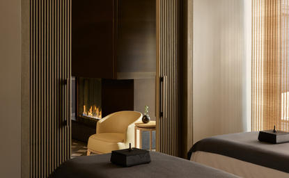 Sala de tratamientos del spa Aman New York con chimenea moderna y mobiliario minimalista.