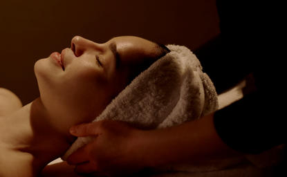 Facial treatment at Aman New York wellness spa, guest receiving skincare with warm towel.