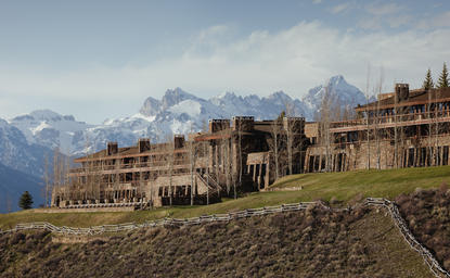 Amangani exterior with snow-capped mountains rising beyond terraced architecture on a hillside.