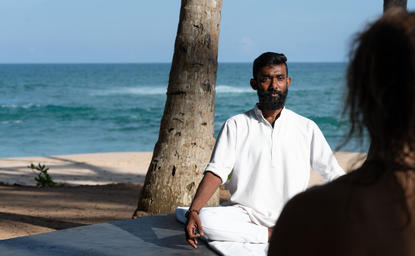Man in white shirt meditating by the beach at Amanwella, Sri Lanka.