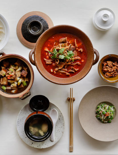 养云安缦度假村的中式餐点俯视图，红色碗中盛放辣味汤菜，配以坚果和蔬菜配菜。