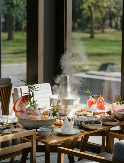 Dining table at Amanyangyun with views across gardens, featuring fresh juices and pastries.