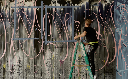Artista al lavoro presso Aman New York, circondato da fili e materiali per l'installazione.