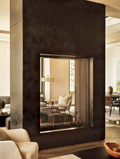 Camino in marmo scuro con cornice in legno chiaro in una suite a tre camere all'Aman New York.