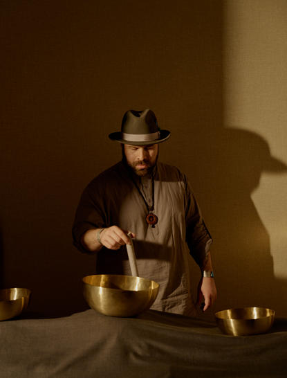 Mulher em sessão de bem-estar no Aman New York, derramando água quente em taça de vidro.
