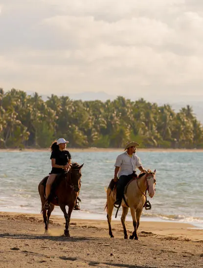 Dos jinetes a caballo en una playa tropical de Amanera resort, República Dominicana.