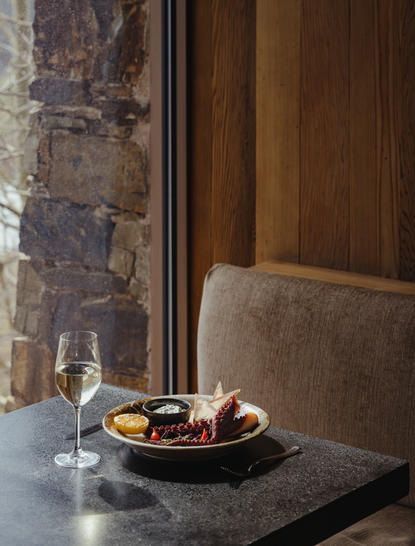 Dining table at Amangani with plated food and stone walls.