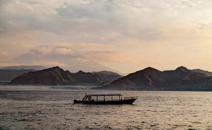 Traditional wooden boat on calm waters at sunrise, Amankila.