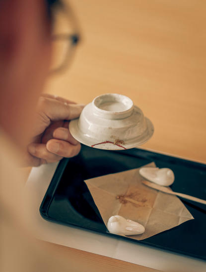 Kintsugi experience at Aman Tokyo: ceramic bowl with gold seams held on black plate with chopsticks.