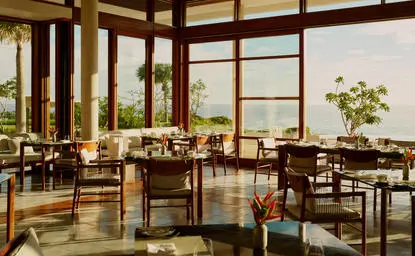 Casa Grande main restaurant at Amanera overlooks Dominican landscape through floor-to-ceiling windows with natural wood furnishings.