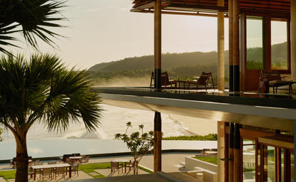 Lounge bar at Amanera resort overlooking tropical coastline and mountains at dusk.