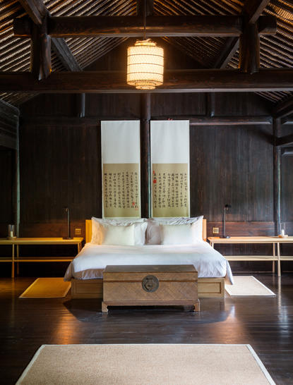 Principal bedroom at Amanfayun with traditional timber ceiling and floor-to-ceiling windows overlooking garden views.