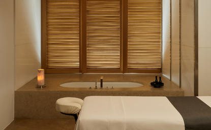 安缦卓熠度假村水疗室内部,配有木质百叶窗、按摩床和温暖的灯光照明。