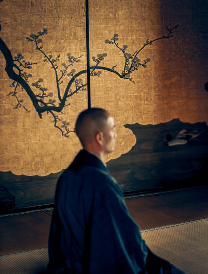 アマン京都のリゾートで、禅の瞑想中に壁の枝のアート作品を眺める人物の横顔。
