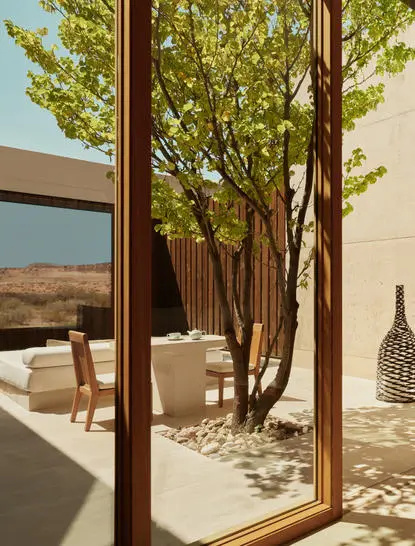 Patio sombreado con árboles y vistas al desierto de Utah en Amangiri resort.