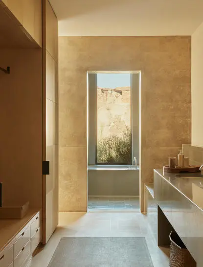 Orchard Suite bathroom at Amangiri with travertine walls and view through doorway to bedroom beyond.
