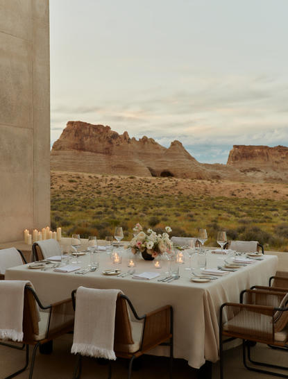 アマンギリ リゾートのプライベート砂漠ダイニングラウンジで、赤い岩山を眺めながら設営されたテーブル。
