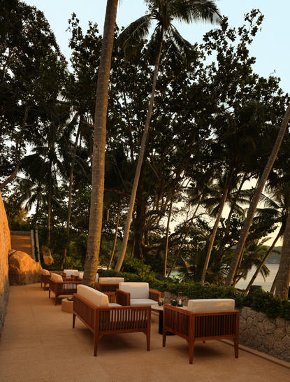 Zwei Holzstühle auf einer Terrasse bei Sonnenuntergang im Amanpuri Resort.