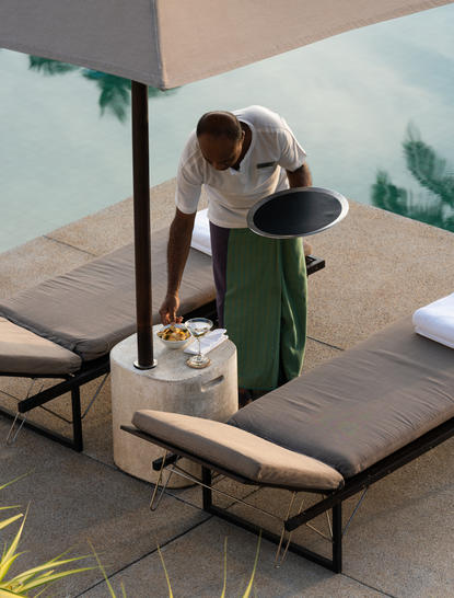 Diner seated at a wooden table at Amanwella in Sri Lanka, enjoying a meal with ocean views.
