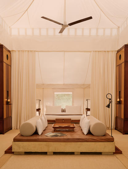 Symmetrical bedroom interior at Aman-i-Khas with draped fabric canopy, two bedside tables and central fireplace.