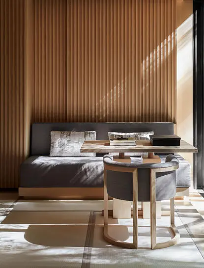 Principal bedroom at Aman Kyoto resort with wooden slat walls and natural light streaming across the bed.