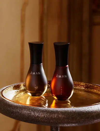 Two dark glass bottles of Aman Essentials toiletries displayed in a shallow bowl at Amandari, Ubud.