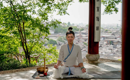 Woman practising yoga on a terrace at Amandayan, surrounded by mountain views and lush greenery.