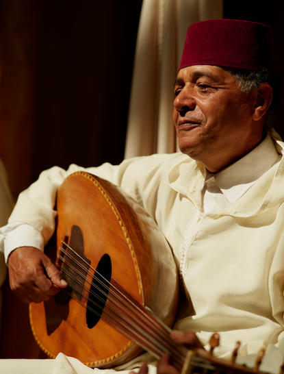 Moroccan musician holding an oud at Amanjena restaurant.
