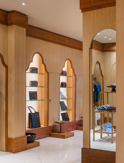 Boutique retail space at Amankila resort with wooden arches, shelving displaying folded clothing and accessories, and warm lighting.