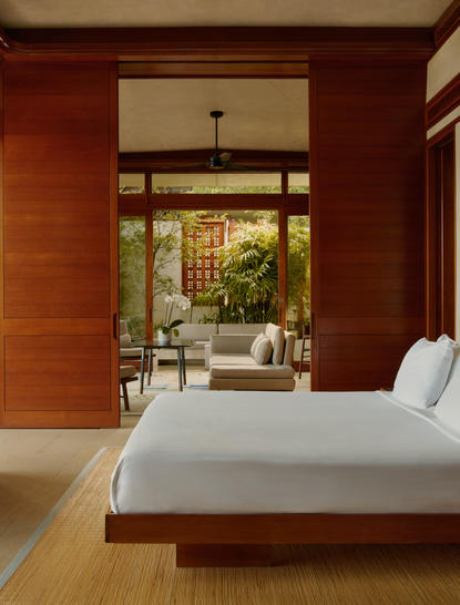 Chambre principale avec lit en bois face aux portes ouvertes donnant sur la végétation, Amanera, Républiquedomicaine.