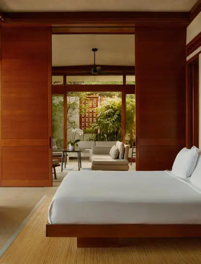 Principal bedroom at Amanera with wooden walls, platform bed, and open doors to garden views.