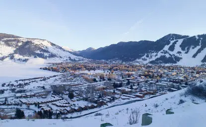 Amangani overlooks the snow-covered town of Jackson nestled in a winter valley below forested mountains.