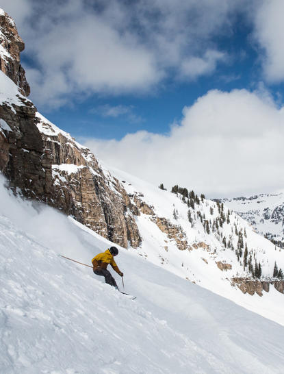 Skier descending snow-covered slope at Amangani, Wyoming, beneath clear blue sky.