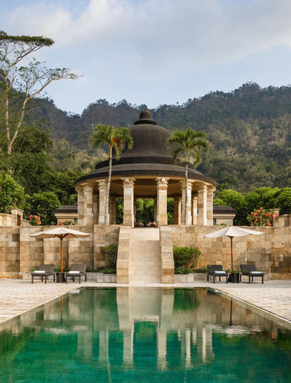 Pavillon à colonnes surplombant un bassin reflétant les montagnes de Java, Amanjiwo resort.