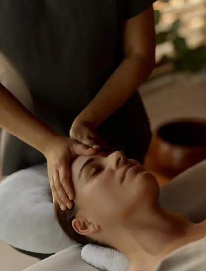 Terapeuta massaggia il viso di una donna durante un trattamento spa ad Amanyara resort.